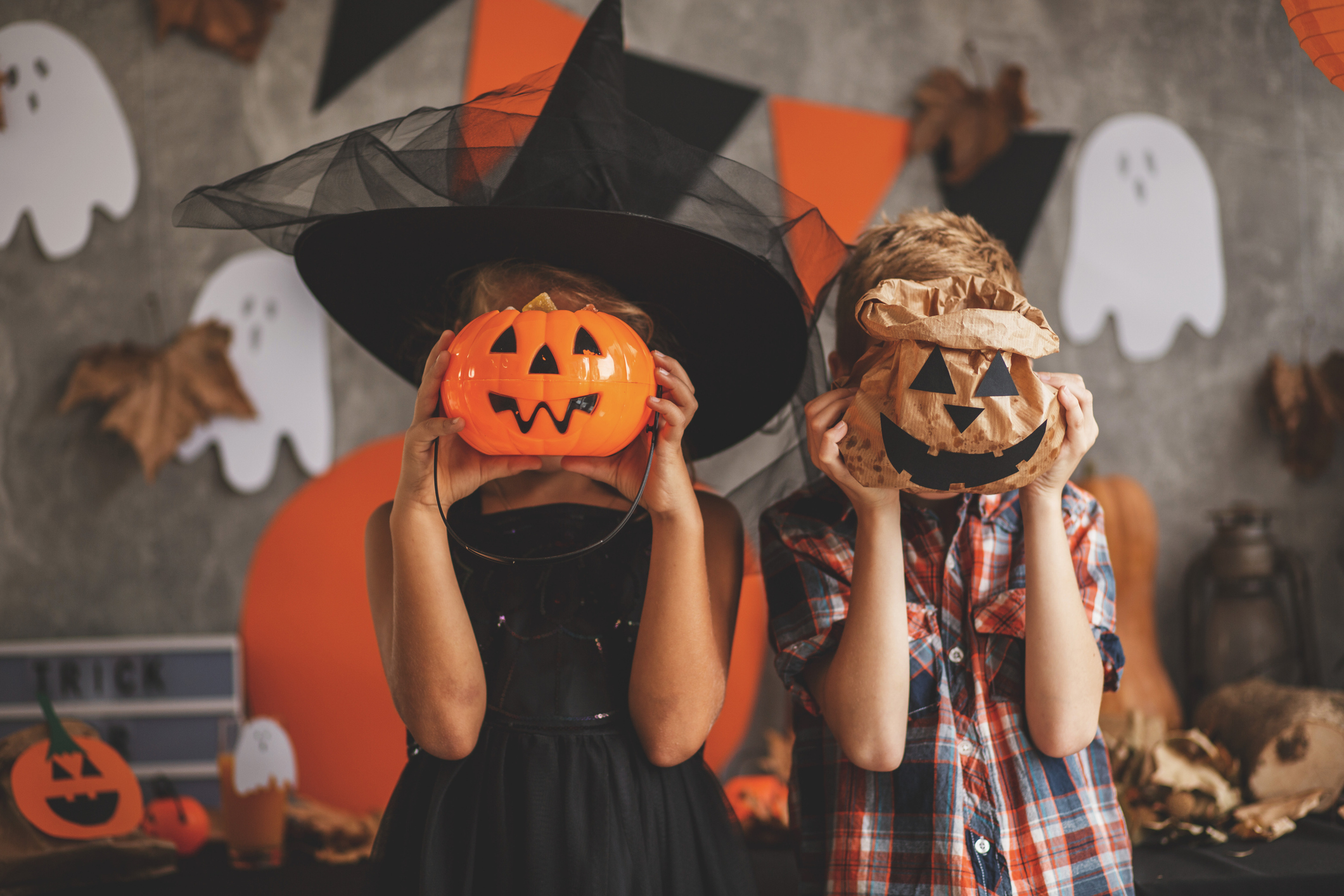 Children playing with Halloween decoration Boy and a girl are playing at the Halloween party, covering their faces with Jack O'Lantern bucket and paper bag.